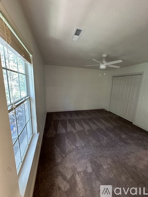 A room with a ceiling fan and a window.