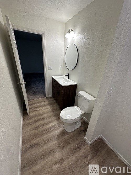 A bathroom with a toilet, sink, mirror, and a door.