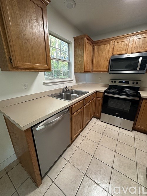A kitchen with wooden cabinets and a stainless steel dishwasher.