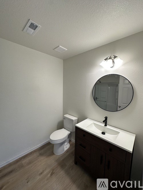 A bathroom with a toilet, sink and mirror.