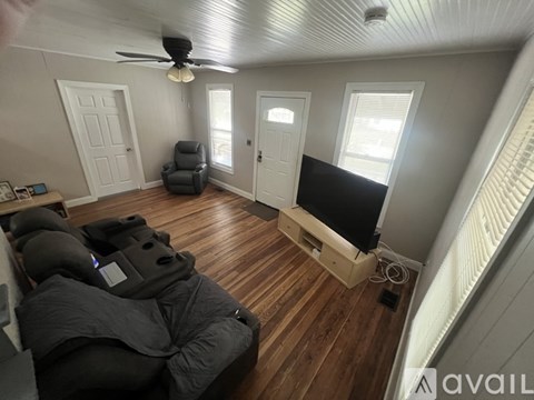 A living room with a grey sofa and a ceiling fan.