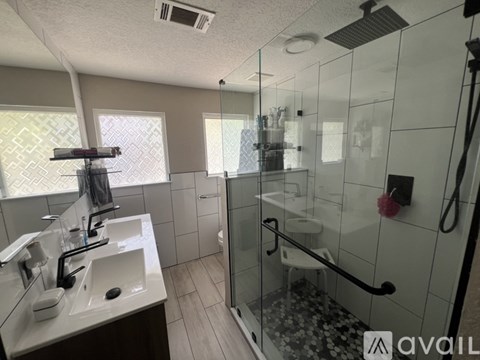 A bathroom with a glass shower stall and a white sink.