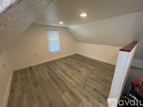 A room with wooden flooring and a window with blinds.