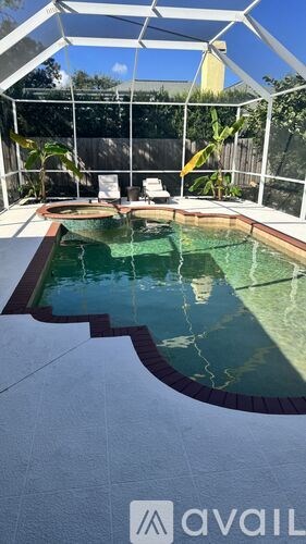 A pool with a glass enclosure and a white chair.