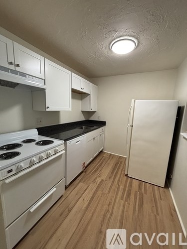 A kitchen with white appliances and wooden floors.