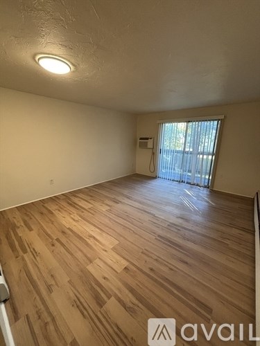 A room with wooden flooring and a window with blinds.