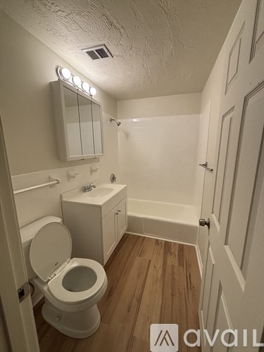 A white toilet with a cabinet and mirror above it.