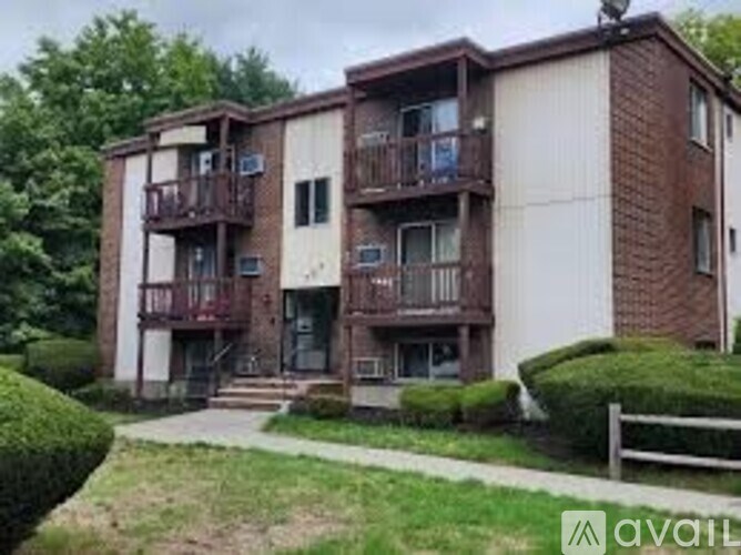 Apartment building with balconies and a small garden in front.