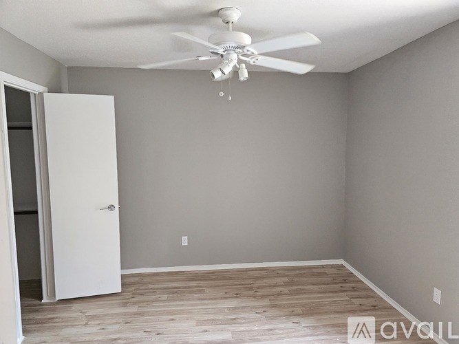 A room with a ceiling fan and a door leading to another room.