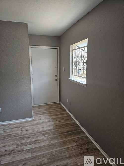 A room with a white door and a window with bars on it.