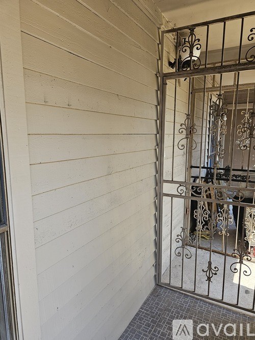A white wall with a metal gate in front of a balcony.