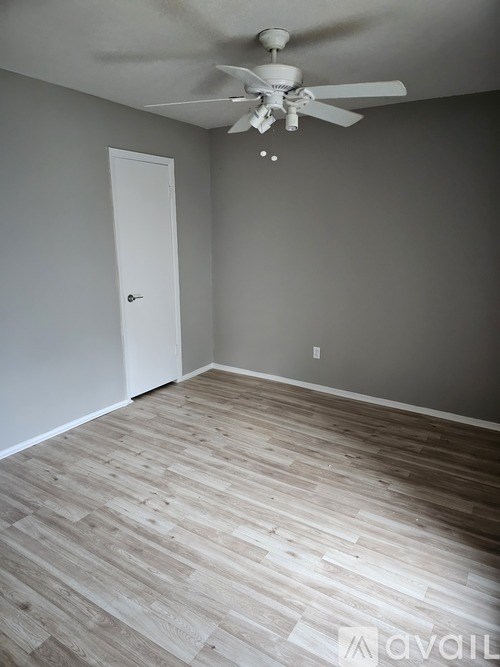 A room with a ceiling fan and wooden flooring.