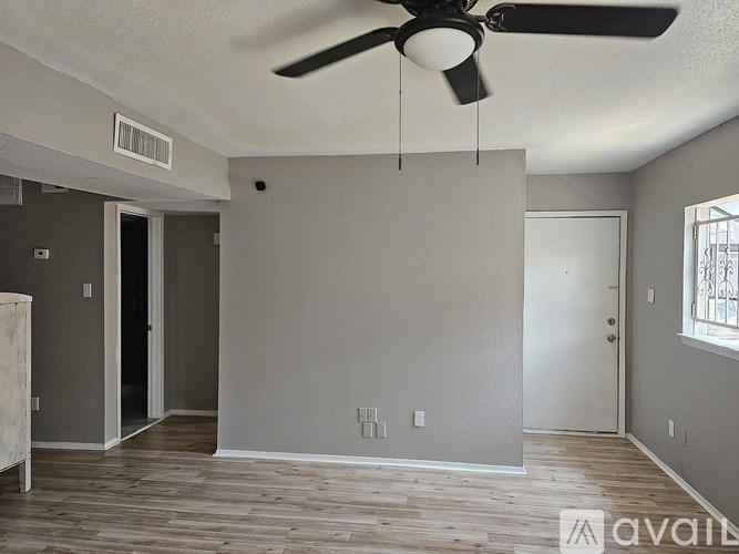 A room with a ceiling fan and wooden flooring.