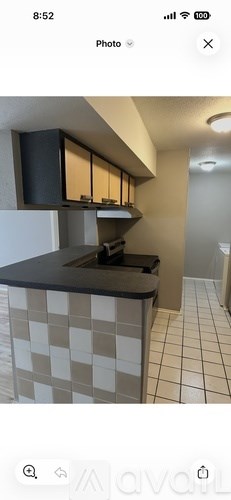 A kitchen with a black countertop and a checkered tile backsplash.