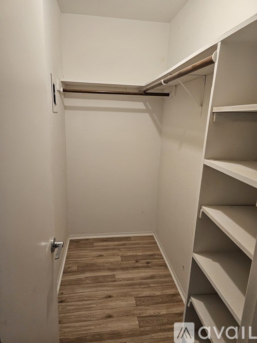 A small, empty room with a wooden floor and white walls.