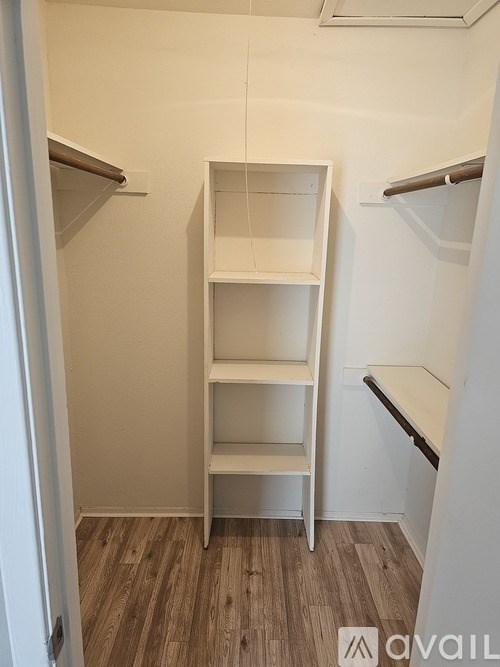 A white shelving unit in a room with wooden flooring.