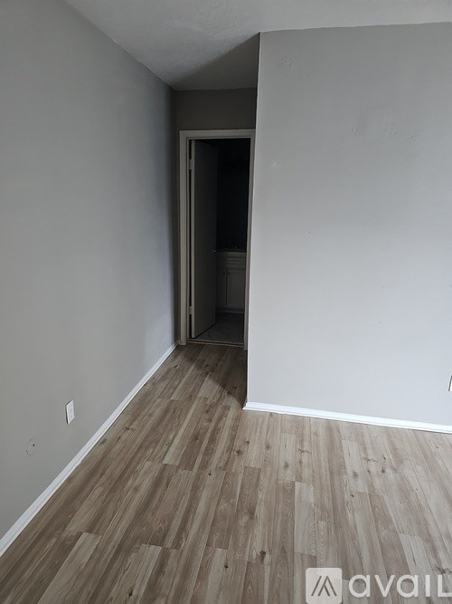 A room with a wooden floor and a doorway leading to another room.