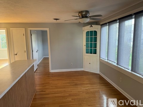 A room with a ceiling fan and wooden floors.