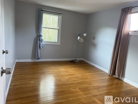 A room with wooden flooring and a window with curtains.
