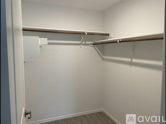 A white closet with a shelf and a door.