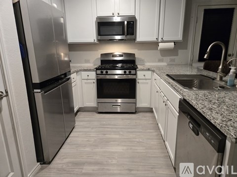 A kitchen with a stainless steel refrigerator, microwave, oven, and sink.