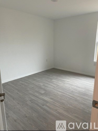 A room with wooden flooring and a door on the right.
