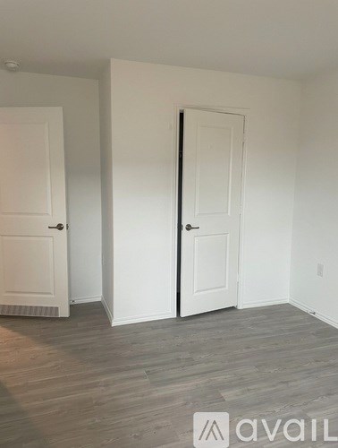 A room with two white doors and wooden flooring.
