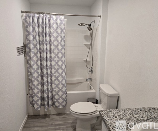 A bathroom with a toilet, a shower with a curtain, and a toilet brush.