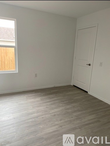 A room with a white door and a window with a wooden frame.