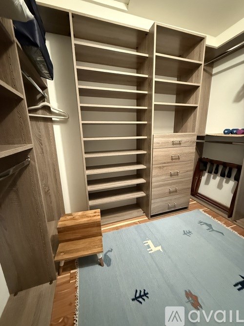 A walk in closet with a bench and a blue carpet.