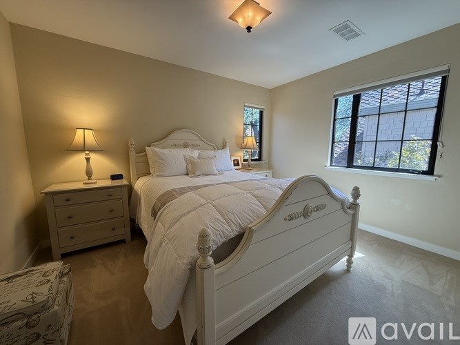 A bedroom with a large bed, a nightstand, and a window.