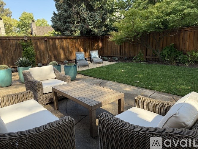 A patio with a table and chairs is surrounded by a wooden fence.
