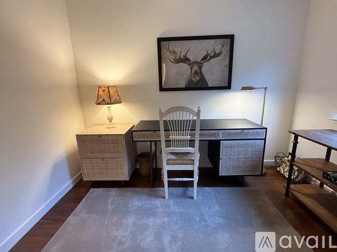 A room with a desk, chair, and a picture of a deer on the wall.