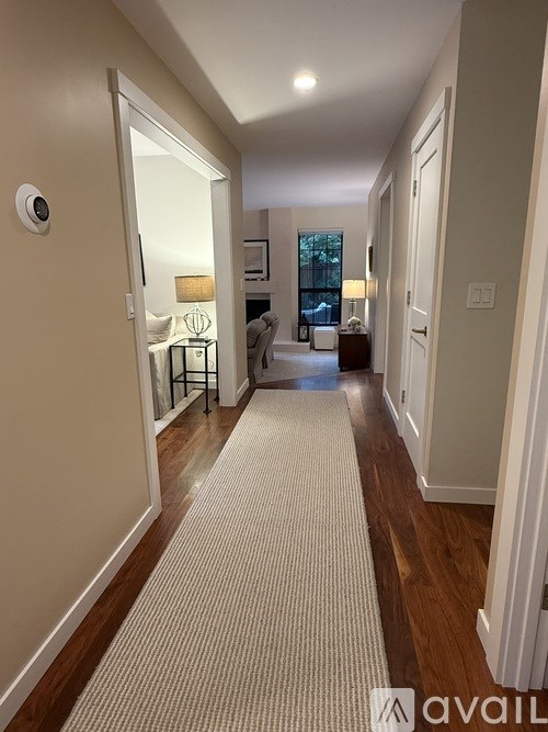 A hallway with a carpeted floor and a door on the left.