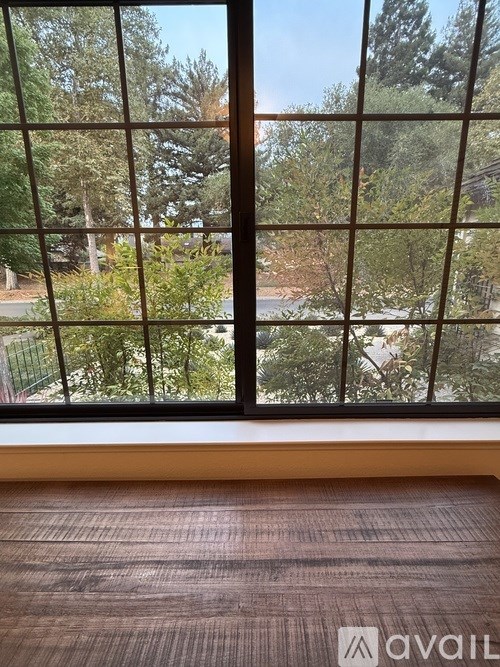 A room with a large window overlooking a tree-filled area.
