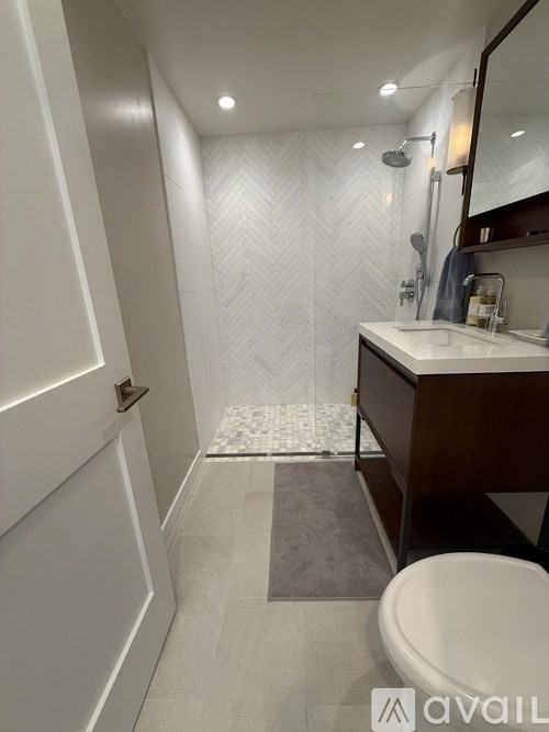A bathroom with a white toilet, sink, and a shower with a white tiled floor.
