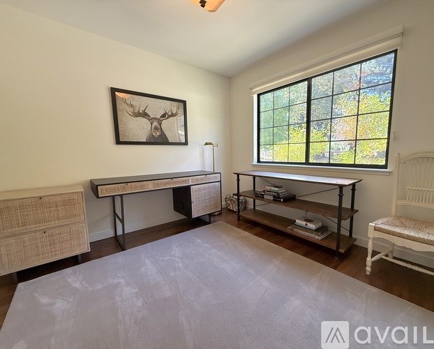A room with a moose head on the wall and a window showing greenery outside.