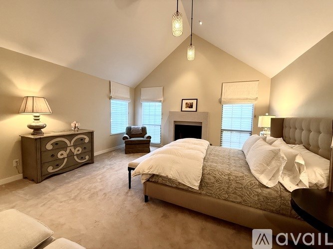 A bedroom with a large bed, a dresser, and a chair.