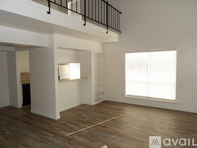 A spacious room with wooden floors and a window with blinds.