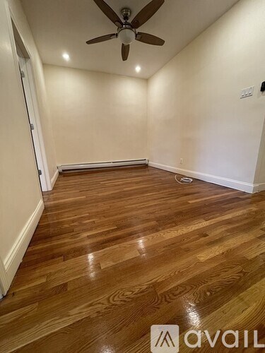 A room with wooden flooring and a ceiling fan.