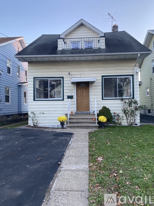A white house with a black roof and a brown door.