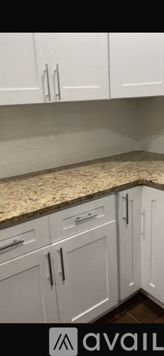A kitchen with white cabinets and a granite countertop.