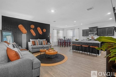 A living room with a grey couch and a coffee table in front of a black wall with orange decorations.