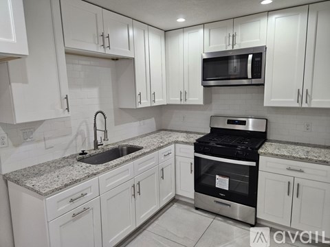 A kitchen with white cabinets and a granite countertop.