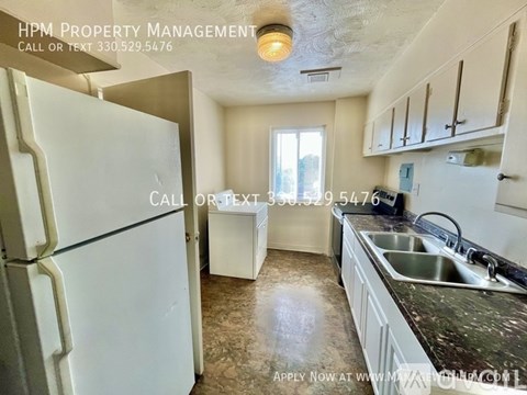 A kitchen with a white refrigerator and a sink with a granite countertop.