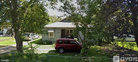 A red car is parked in front of a house.