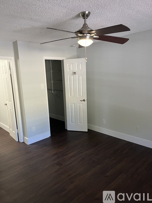 A room with a ceiling fan and wooden floors.