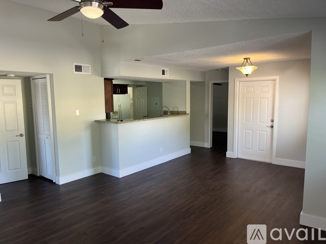 A spacious room with a ceiling fan and wooden flooring.