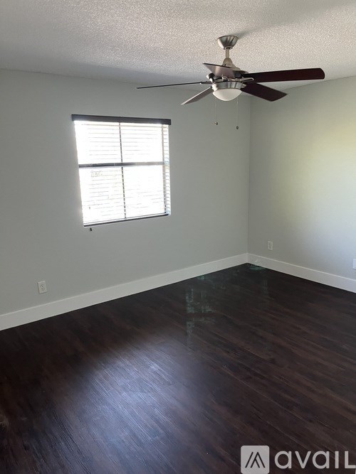 A room with a ceiling fan and a window with blinds.