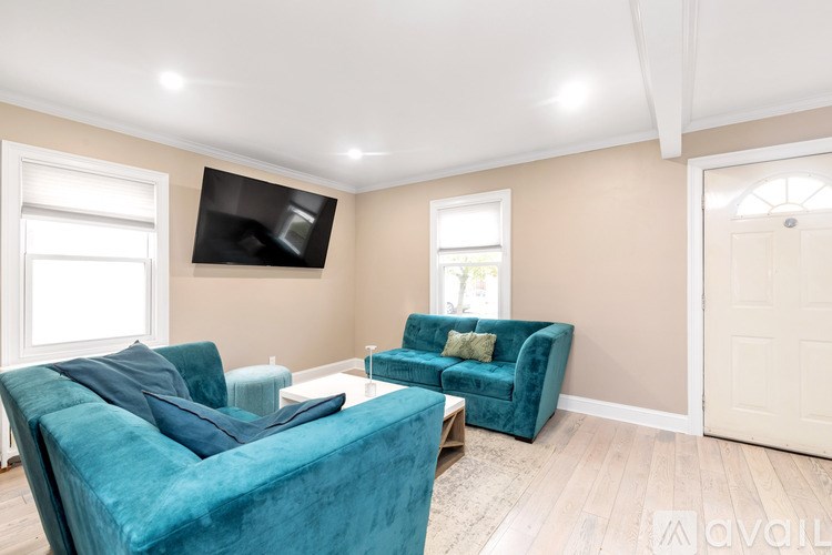 A living room with a blue velvet sofa and a flat screen TV mounted on the wall.